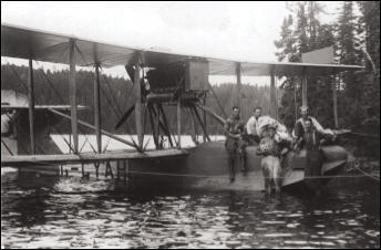 A group of people standing on a biplane in the water.