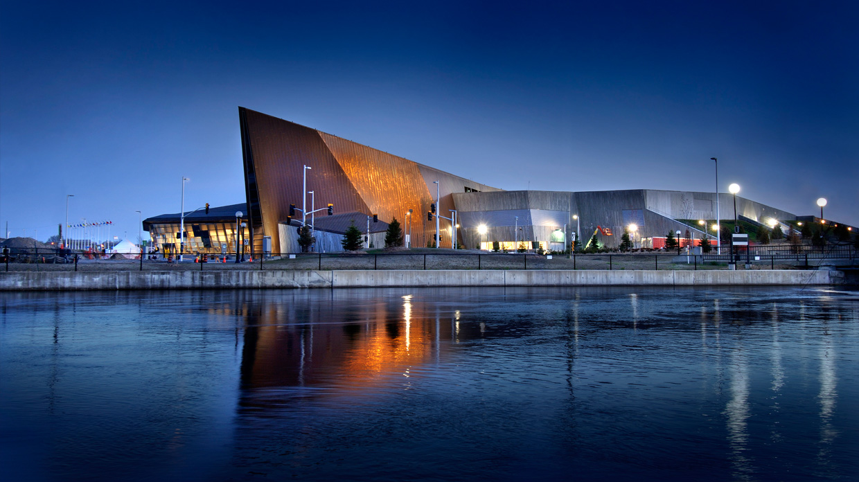 The Canadian War Museum in Ottawa is beautifully lit up at night, reflecting its stunning architecture in the nearby body of water.