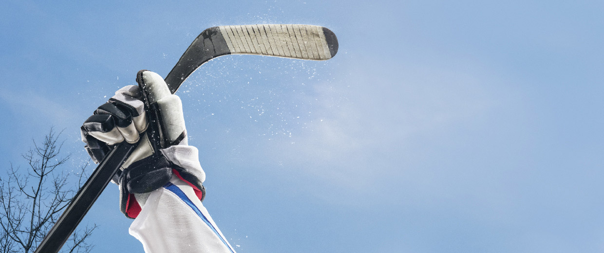 A hockey player is holding a stick in the air at the Canadian War Museum.