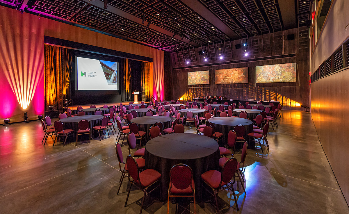 The Barney Danson Theatre with tables and chairs arranged around a projection screen.