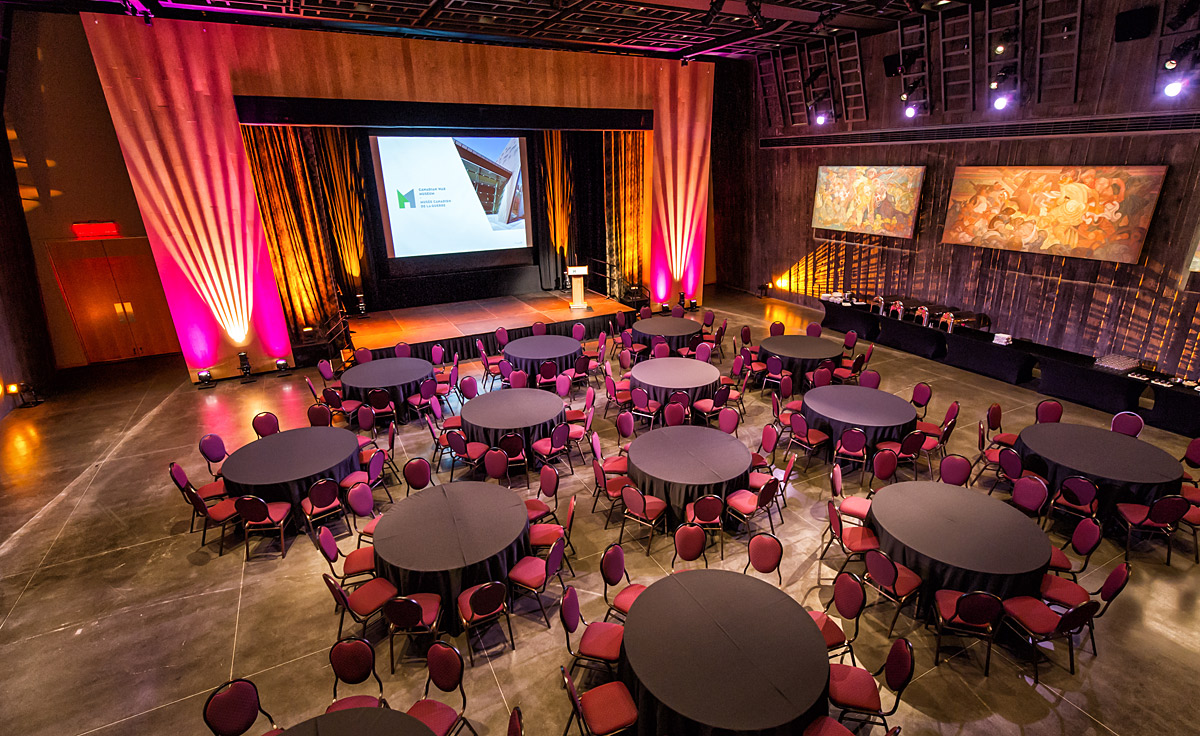 A large room with tables and chairs set up for an event in the Barney Danson Theatre