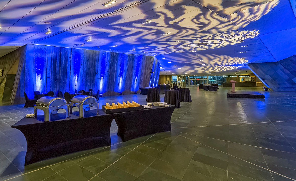 Located in Ottawa, the Canadian War Museum boasts a large room with blue lighting and tables.