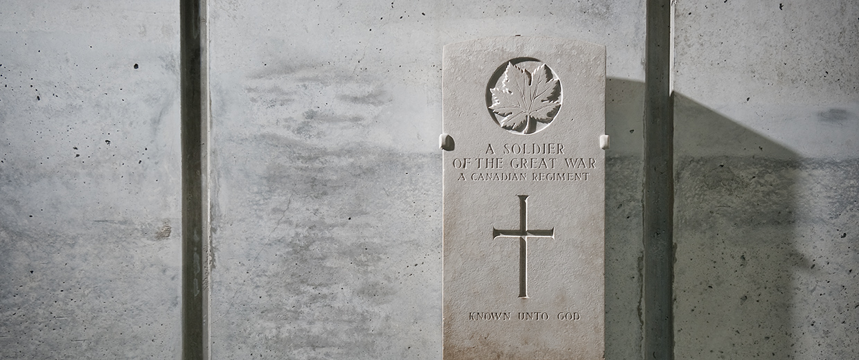 A gravestone with a cross on it next to a concrete wall at the Canadian War Museum in Ottawa.