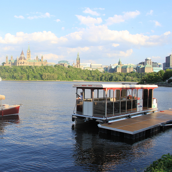 An aqua taxi surrounded by a body of water with the parliament buildings in the background.