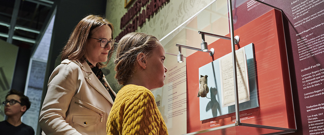 A woman and a child, visiting the Canadian War Museum in Ottawa, are captivated by a display of artifacts.