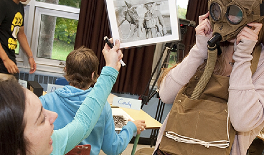 A group of people in a classroom a learning about war gas masks.