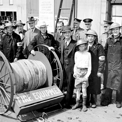 Visitors at the Canadian War Museum in Ottawa standing next to a large fire hose.