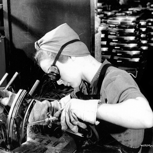 An old photo of a woman working on a machine at the Canadian War Museum.