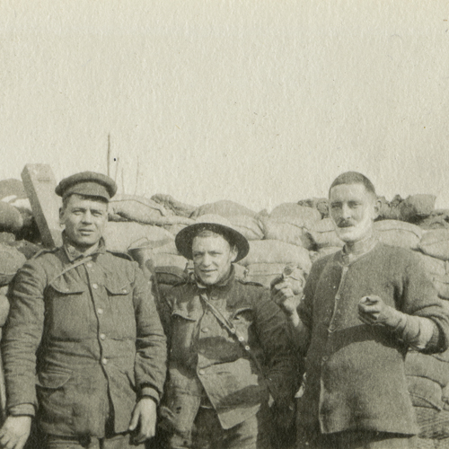 A group of soldiers standing next to a pile of sand bags