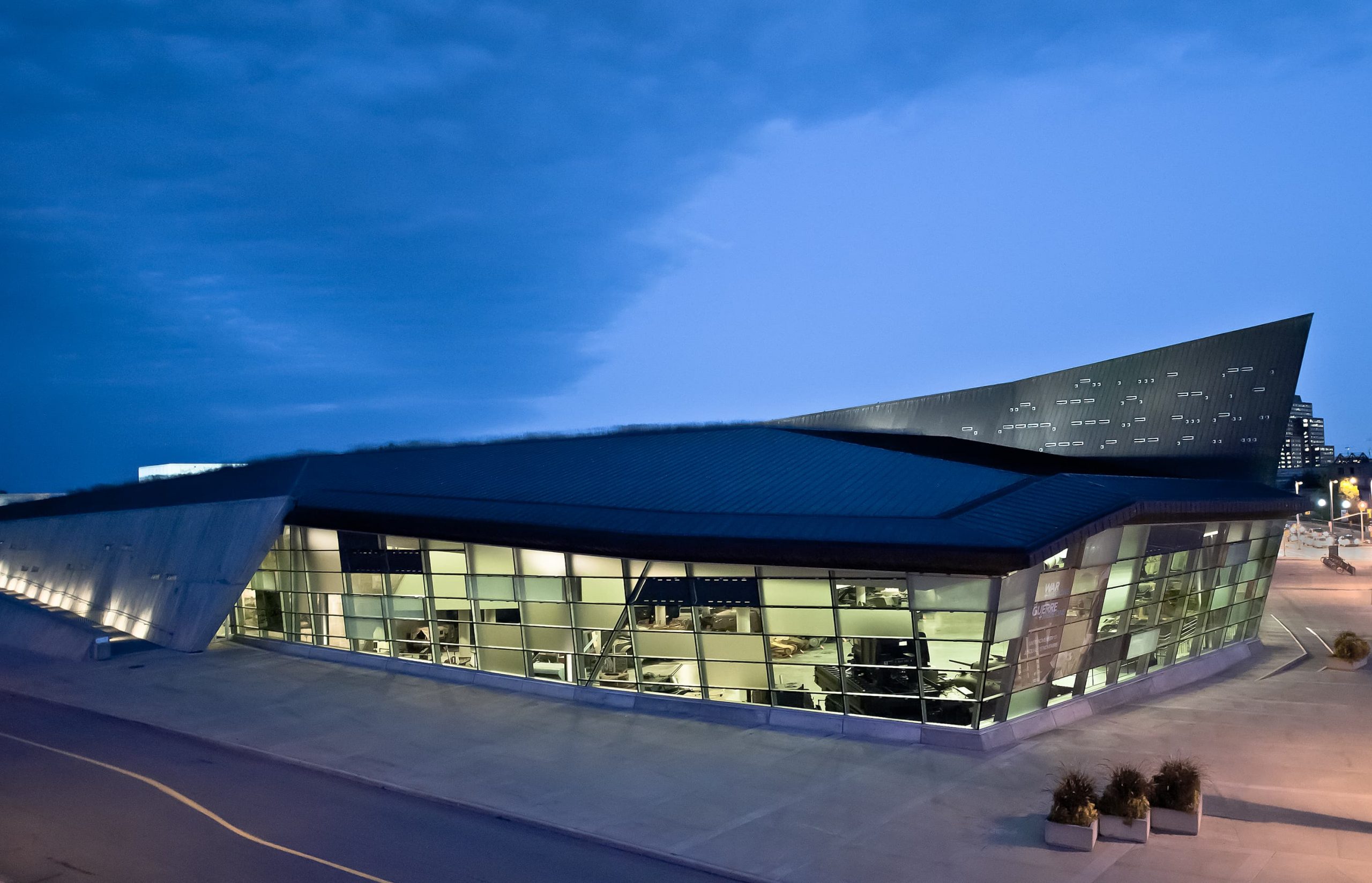 The Canadian War Museum, located in Ottawa, a stunning building that is beautifully illuminated in the night sky.