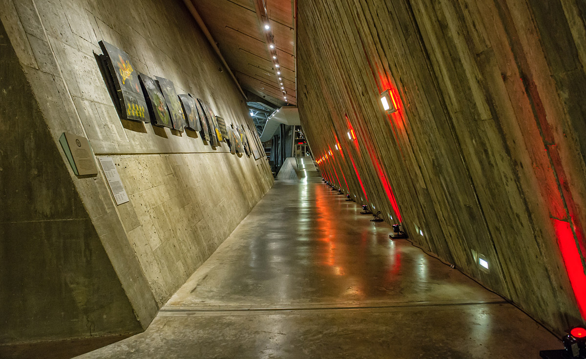 A long corridor at The Canadian War Museum in Ottawa with paintings on the concrete walls.