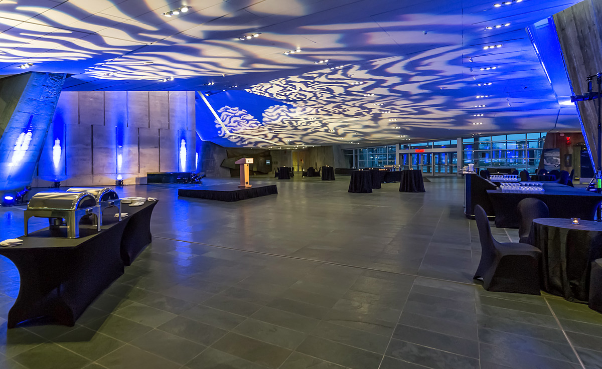 The Lobby with tables and chairs at the Canadian War Museum, complemented by striking blue lighting.