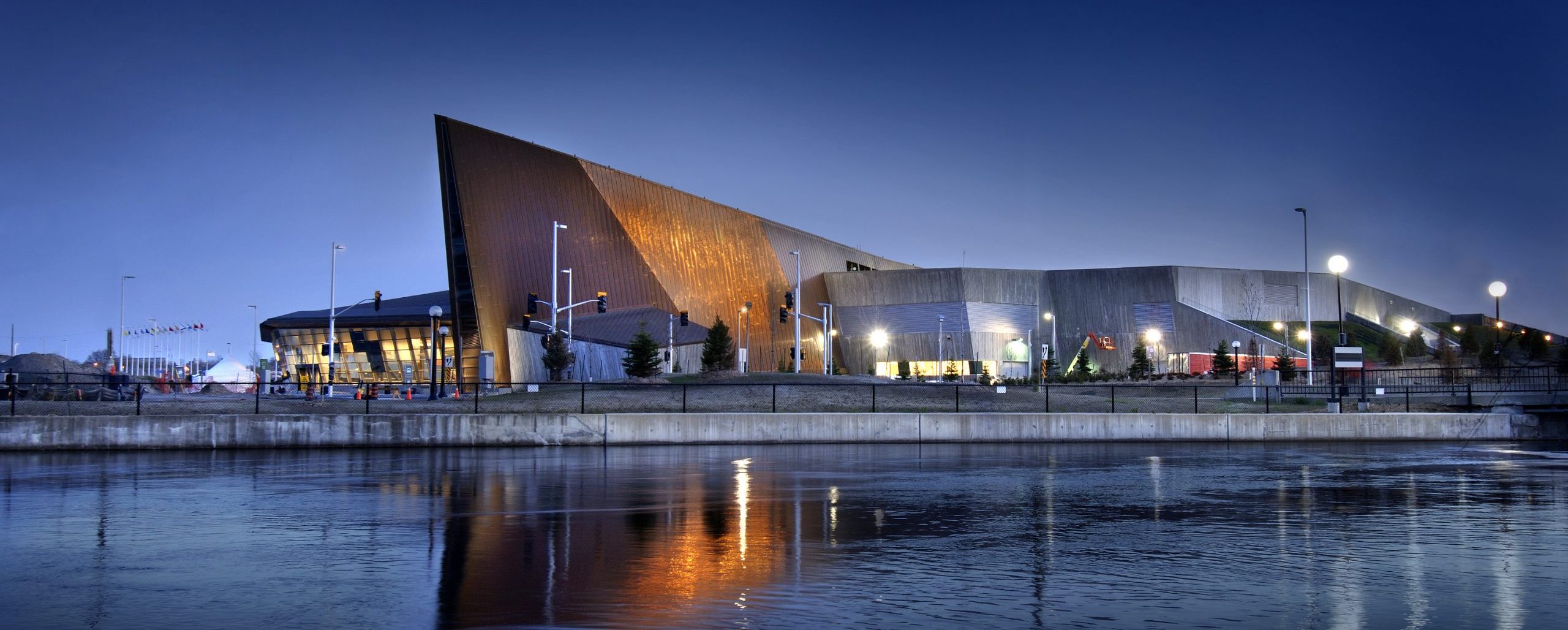 The Canadian War Museum in Ottawa is beautifully lit up at night, reflecting on the adjacent body of water.