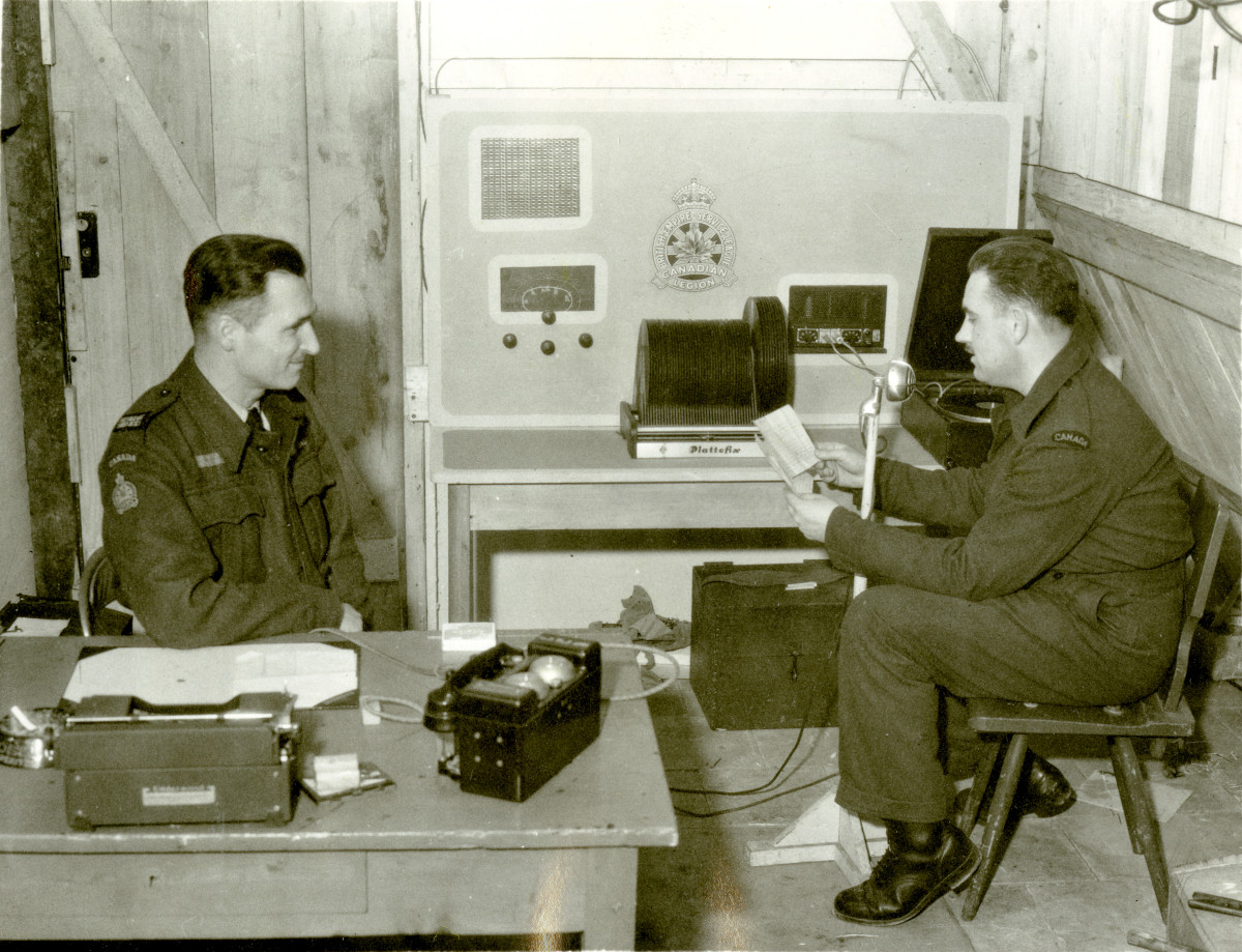 Two men in military uniforms sitting at a table.