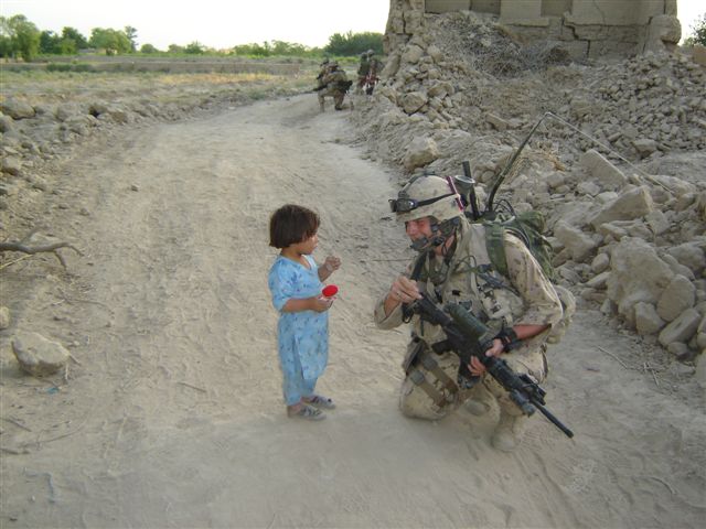 A soldier and a child on a dirt road in Afghanistan.