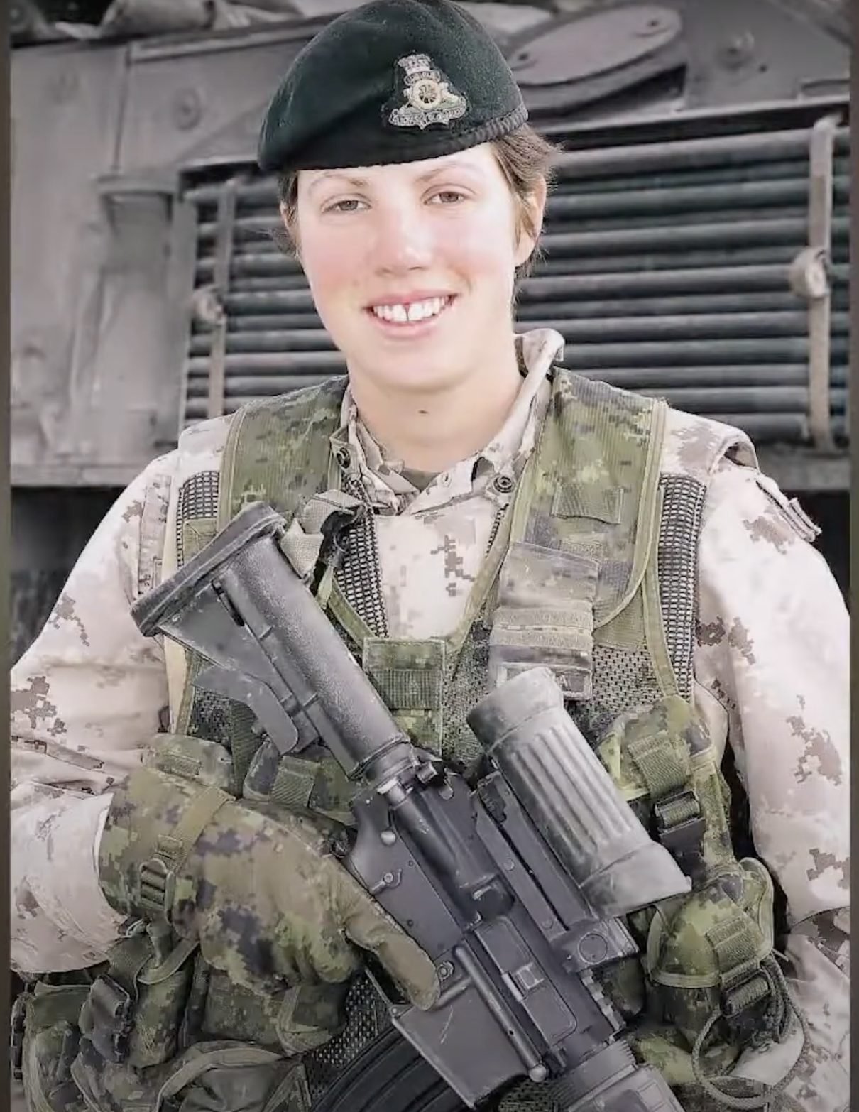 Nichola Goddard holding a rifle in front of a military vehicle.