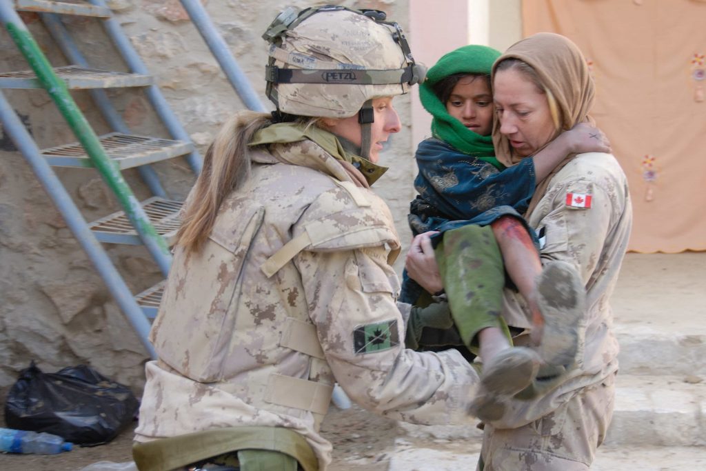 A woman in a military uniform is holding a child outside the Canadian War Museum in Ottawa.