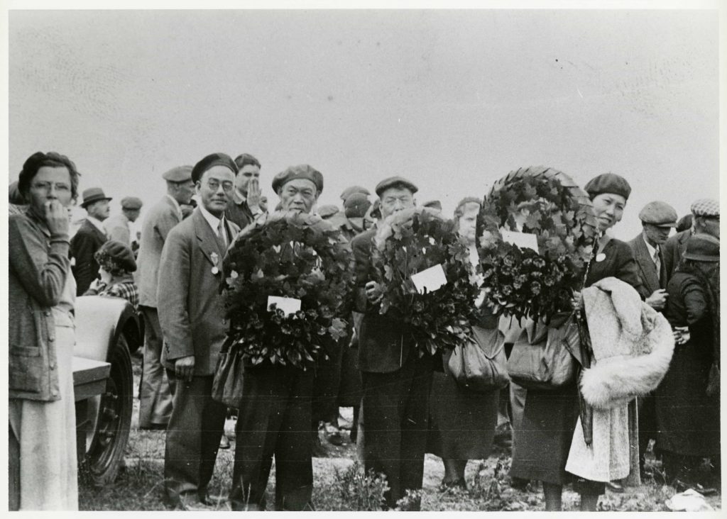 A group of people holding wreaths in the Canadian War Museum field in Ottawa.