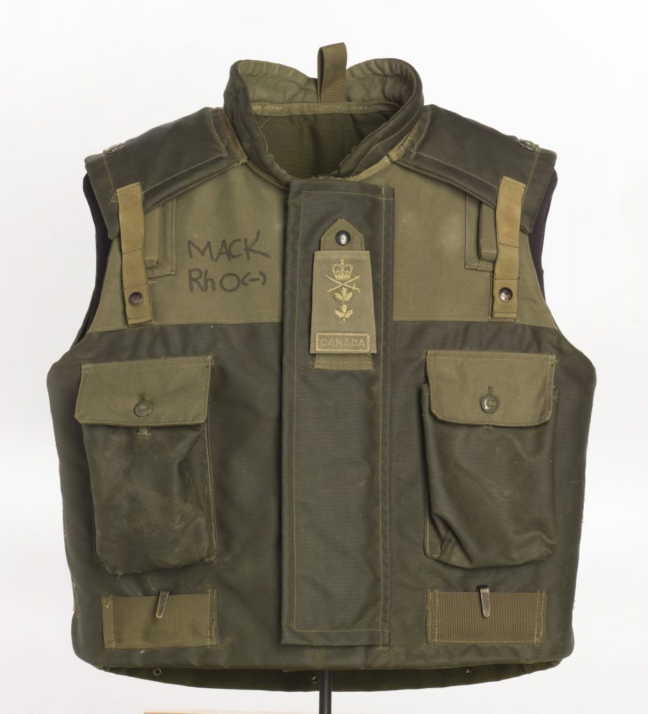 A green and black vest with a pocket on it, showcased at the Canadian War Museum in Ottawa.