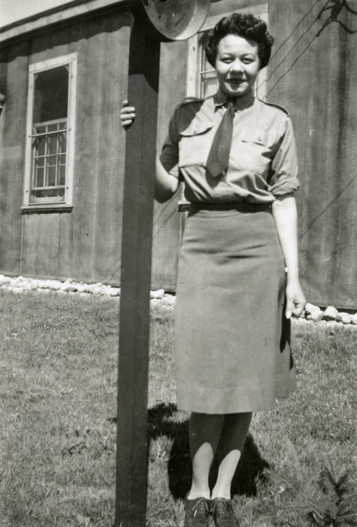 Minnie Gray in a uniform standing next to a pole.