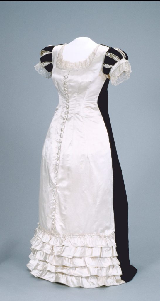 A white and black dress with ruffles displayed on a mannequin .