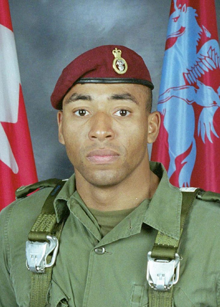 A Canadian soldier wearing a beret in front of Canadian flags at the Canadian War Museum in Ottawa.