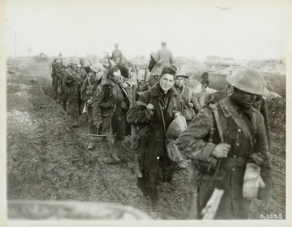 Soldiers walking through mud with all their gear.