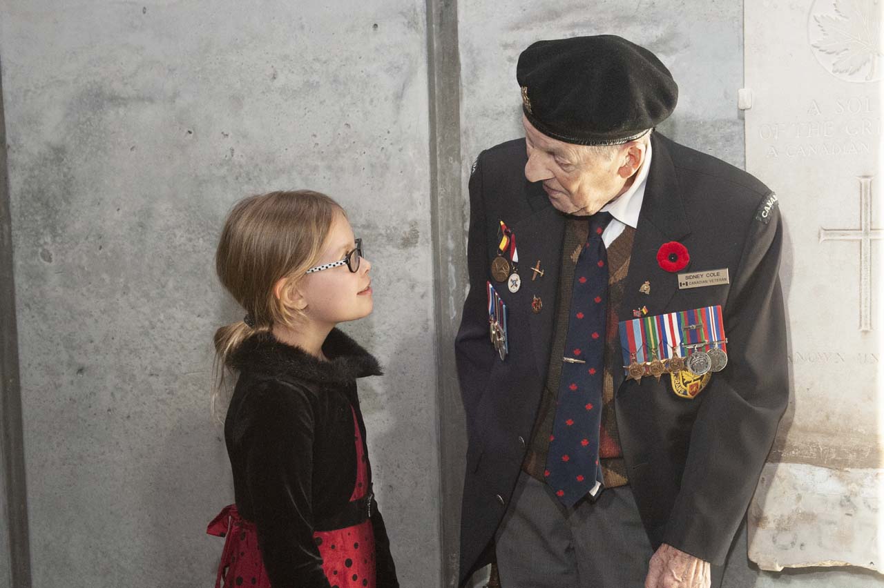 A young girl is talking to an old man in a suit.