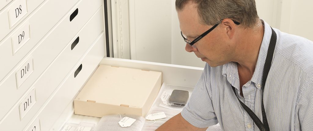 A man looking at a file in a drawer.