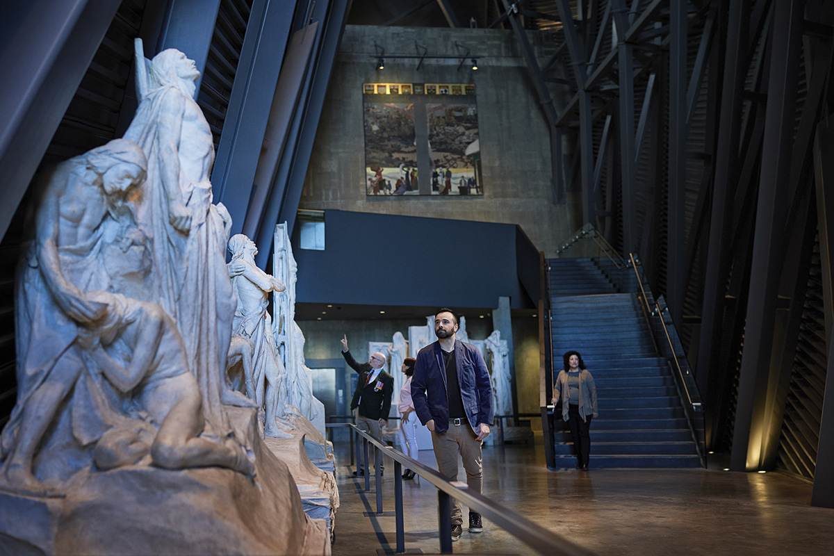 A group of people walking through a museum with statues.