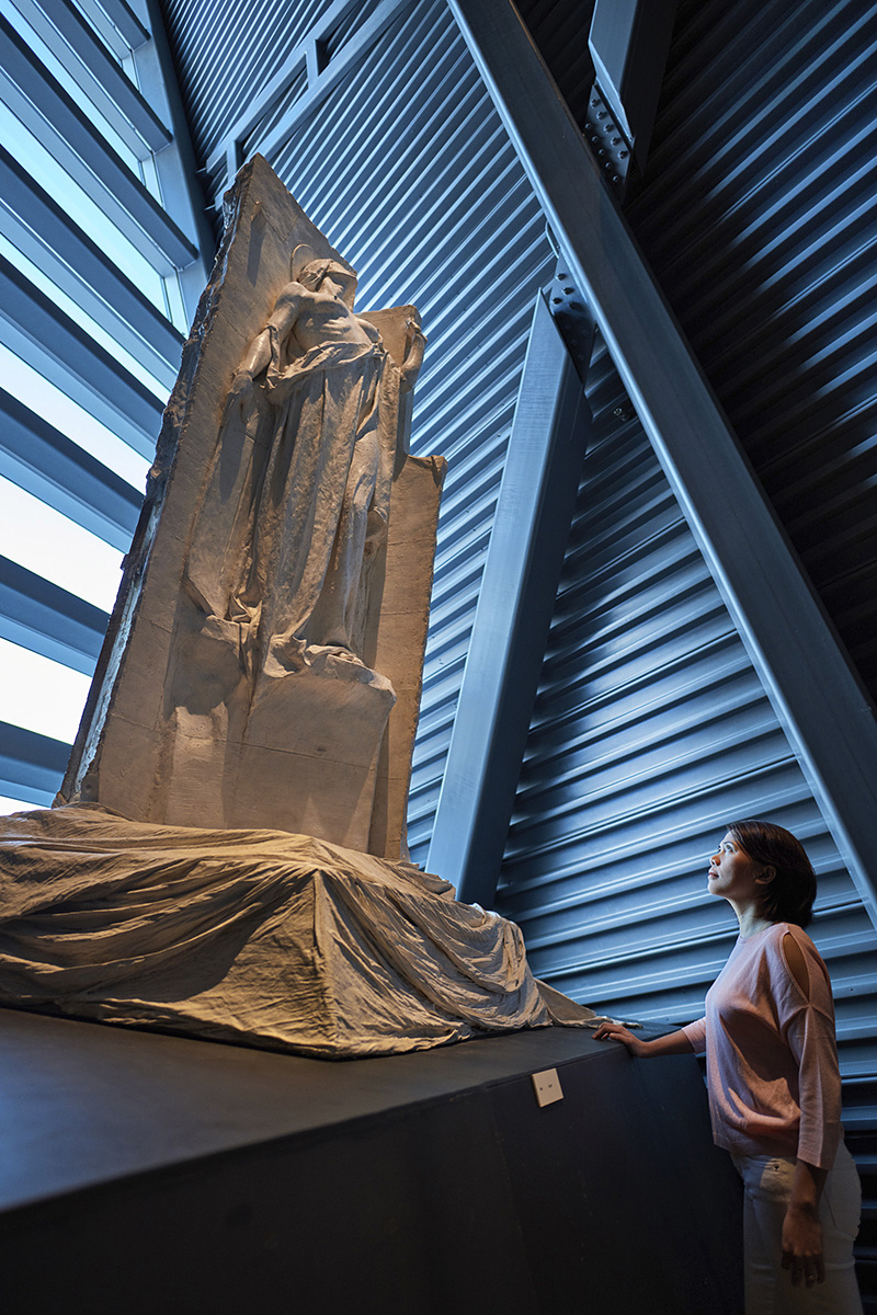 A woman looking at a sculpture in a museum.