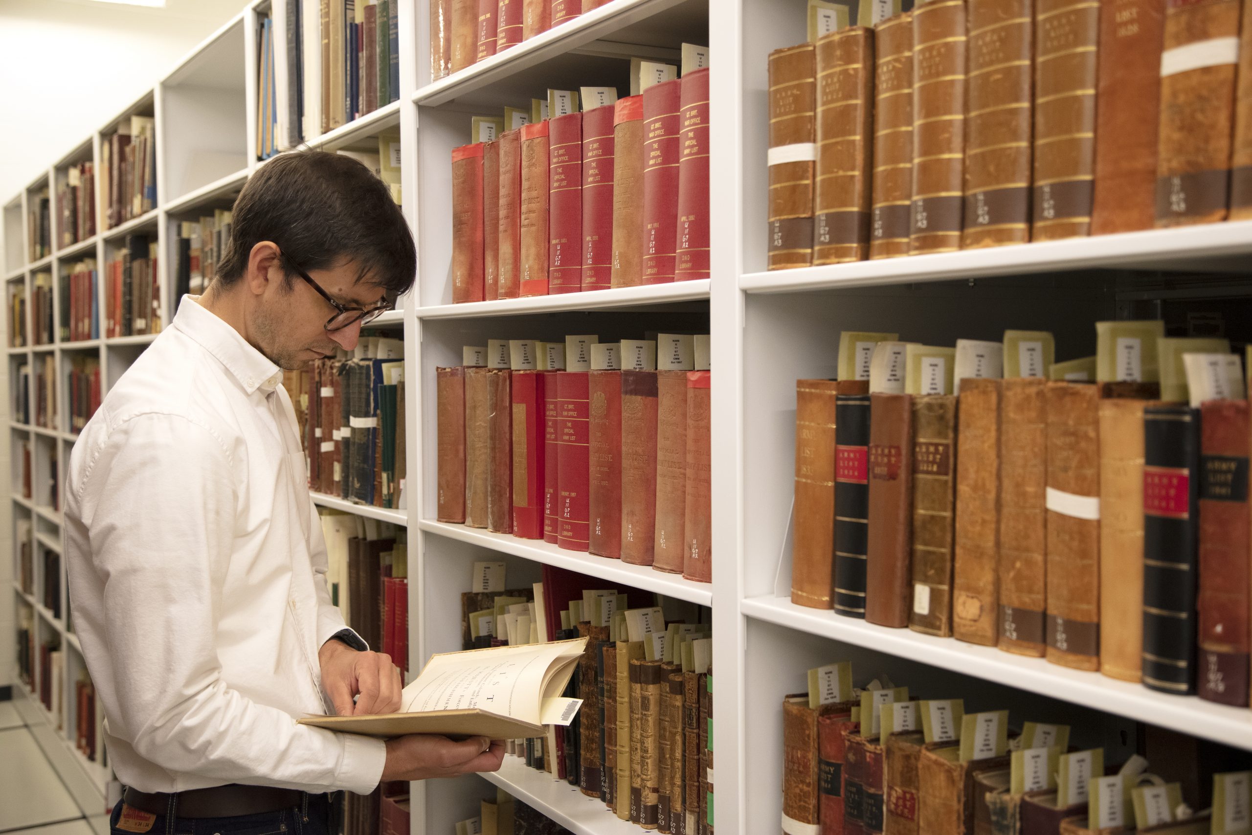 Man reading a book in a isle of a library