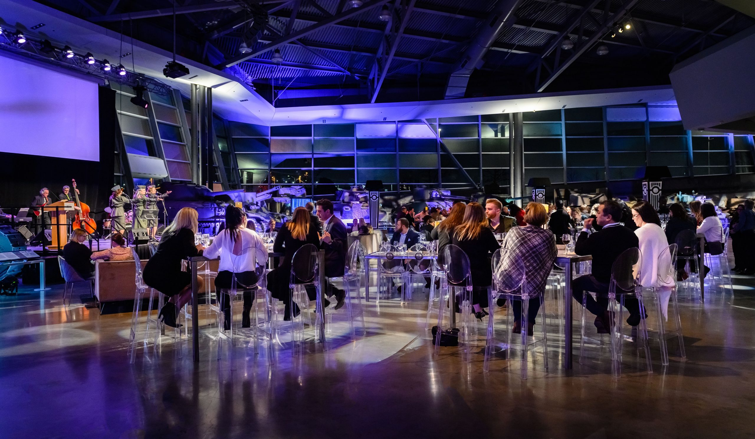 Tables set up inside a purple-lit conference space at nighttime